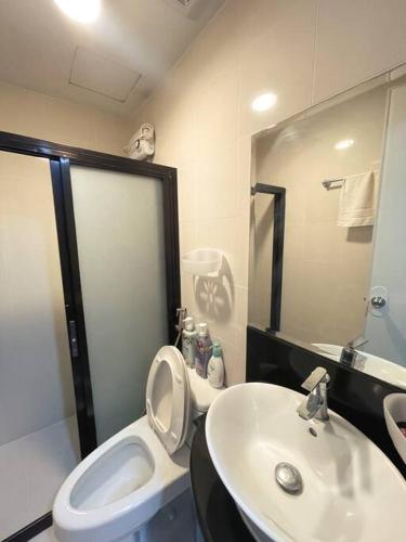 a bathroom with a white toilet and a sink at Lovely & Stylish 1BR in Mckinley Hill with View in Manila