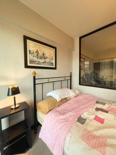 a bedroom with a bed and a table with a lamp at Lovely & Stylish 1BR in Mckinley Hill with View in Manila