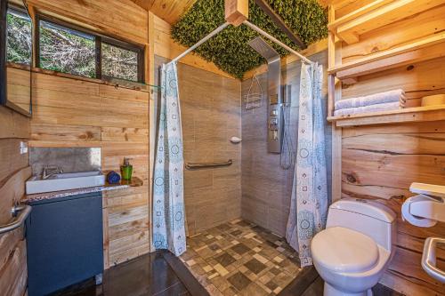 uma casa de banho em madeira com um WC e um chuveiro em Tiny House Jaulares em Rivas