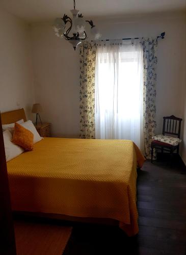 a bedroom with a yellow bed and a window at Oliveira Country House in Figueira e Barros