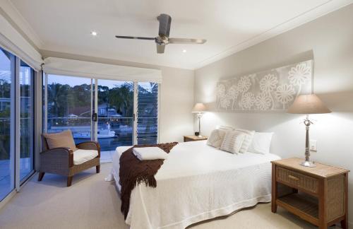 a bedroom with a bed and a chair and a window at 20 Wesley Court, Noosa Heads in Noosa Heads