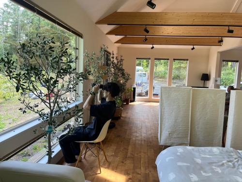 Ein Mann, der auf einem Stuhl sitzt und ein Foto von einem Schlafzimmer macht. in der Unterkunft Hororo Style in Shimo-setsuri