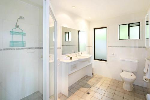 a white bathroom with a toilet and a sink at 21 Arakoon Crescent, Sunshine Beach in Noosa Heads