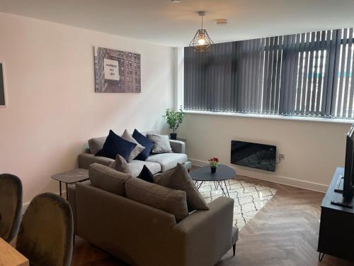 a living room with two couches and a fireplace at Modern City Centre Apartment in Birmingham