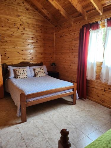 1 dormitorio con 1 cama en una cabaña de madera en Cabañas Celi en Esquel