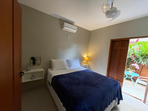 a bedroom with a bed with a blue blanket and a window at Confraria da Prata Flats in Pirenópolis