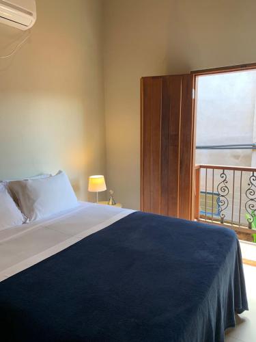 a bedroom with a bed with a large window at Confraria da Prata Flats in Pirenópolis
