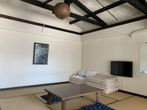 Una sala de estar con una mesa y un televisor. en Hotel & Restaurant On the Beach Lue, en Motobu