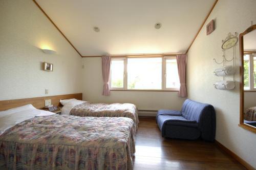 a hotel room with two beds and a chair at Pension Field in Hokuto