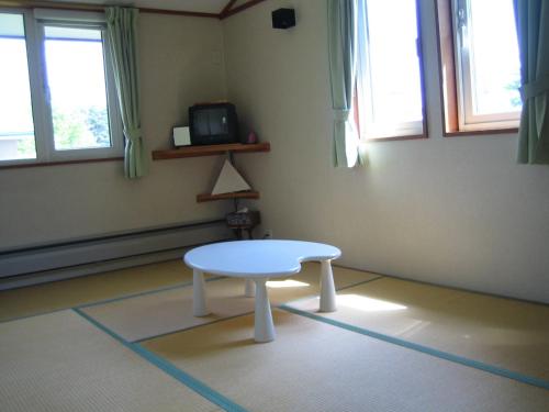 a white coffee table in a room with windows at Pension Field in Hokuto