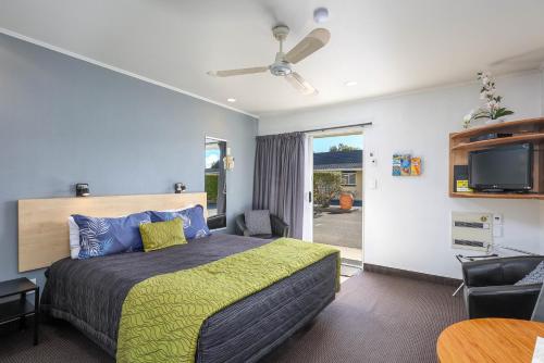 1 dormitorio con 1 cama y TV de pantalla plana en ASURE Fountain Resort Motel, en Nelson