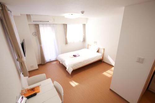 um pequeno quarto branco com uma cama e uma janela em Connect Inn em Osaka