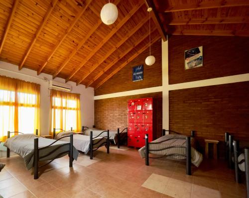 um quarto com três camas e uma porta vermelha em Hostel Bahía Ballenas em Puerto Pirámides