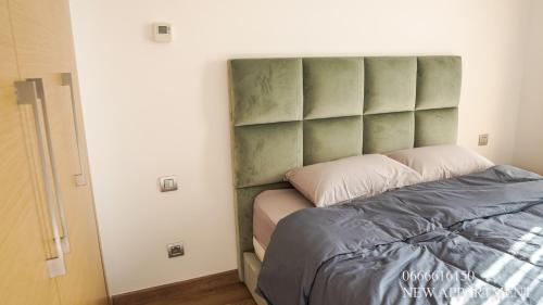 een slaapkamer met een bed met een groen gewatteerd hoofdeinde bij New prestigia in Rabat