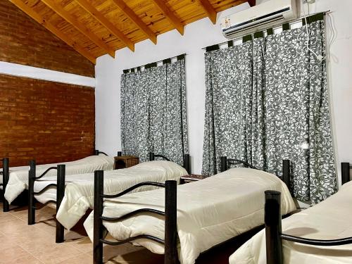 three beds in a room with black and white curtains at Hostel Bahía Ballenas in Puerto Pirámides