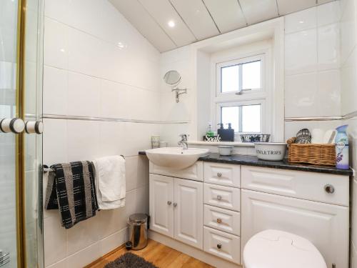 a white bathroom with a sink and a mirror at Buzzards Rest in Morpeth