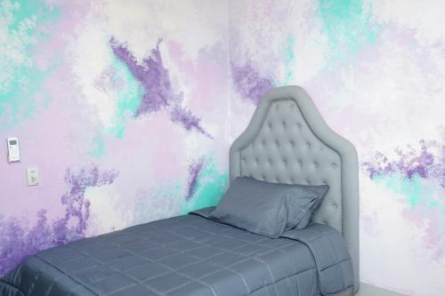 a bedroom with a bed with a purple and green wall at Apartamento moderno y centrado en Barranquilla in Barranquilla