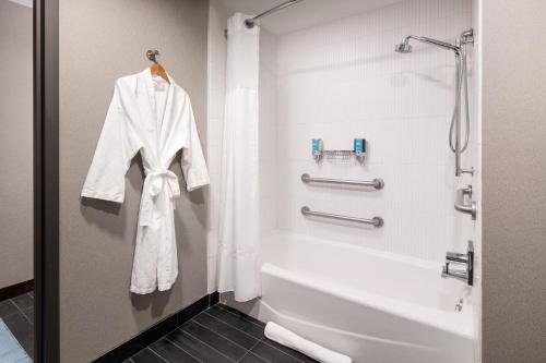 a bathroom with a bath tub and a white robe at Aloft Cupertino in Cupertino