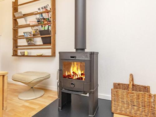 a wood stove in a living room with a chair at 6 person holiday home in Karrebæksminde-By Traum in Karrebæksminde