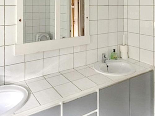 a white tiled bathroom with two sinks and a mirror at Holiday home Tynset in Tynset