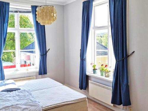 um quarto com cortinas azuis e uma cama e duas janelas em Holiday home Utansjö em Utansjö