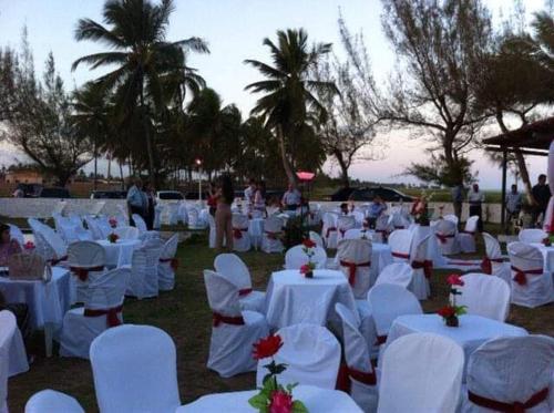 a group of white tables and white chairs and palm trees at Pousada Cataventos in Sirinhaém