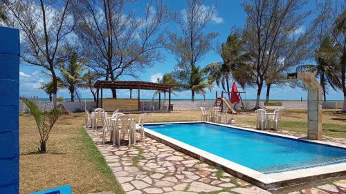 a swimming pool with chairs and a playground at Pousada Cataventos in Sirinhaém