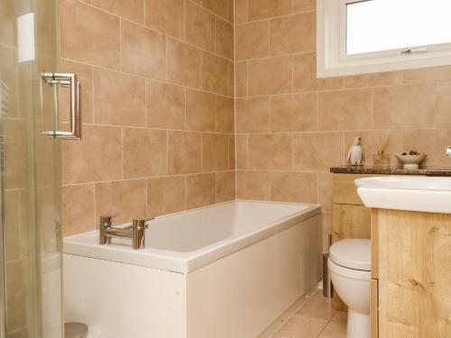 a bathroom with a tub and a toilet and a sink at New Cottage in Wooler
