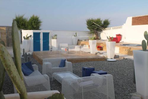 a patio with white chairs and blue chairs at Beauty Beach Villa in Monopoli