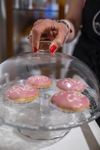 a woman holding a glass plate with pink cookies on it at Il Giardino Di Epicuro in Rocca San Giovanni