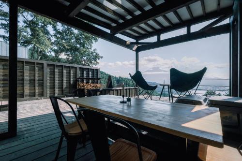 a wooden deck with a wooden table and chairs at つながるキャンプリゾートQOONEL+ in Azagawa