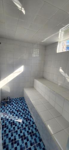 Habitación vacía con paredes blancas y azulejos azules. en Apartasol Ciudadela Santafe - Santa Fe de Antioquia, en Santa Fe de Antioquia