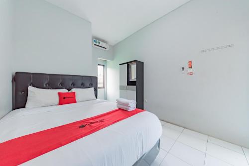 a bedroom with a large bed with a red blanket at RedDoorz Syariah near RS Hermina Sukabumi in Sukabumi