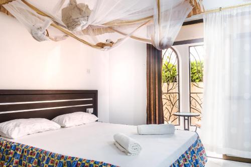 1 dormitorio con 1 cama con 2 toallas en Uhai Vacations en Diani Beach