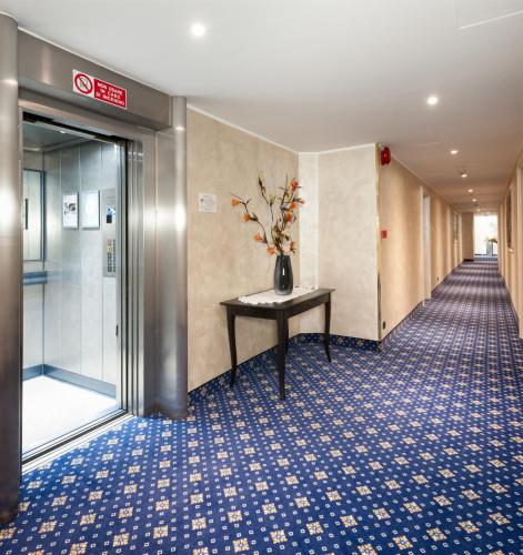 a hallway with a table with a vase of flowers on it at Hotel Lombardia in Milan