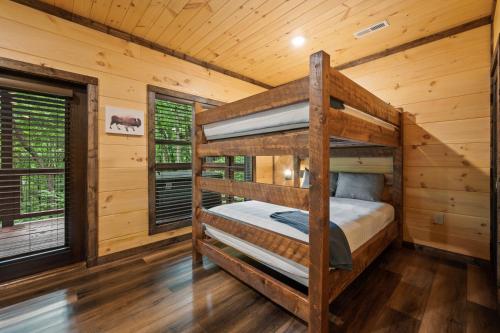 a bedroom with two bunk beds in a log cabin at New Cozy Mountain Cabin Hot Tub Near Downtown in Gatlinburg