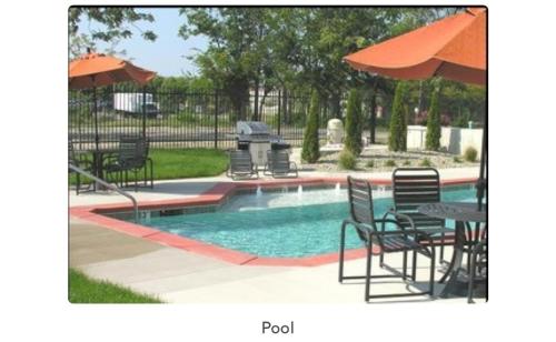 a pool with chairs and tables and an umbrella at Luxury Cozy Loft Downtown STL in Saint Louis