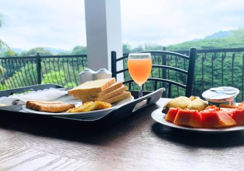 un tavolo con vassoio di cibo e un bicchiere di succo d'arancia di Hanthana Mount View a Kandy