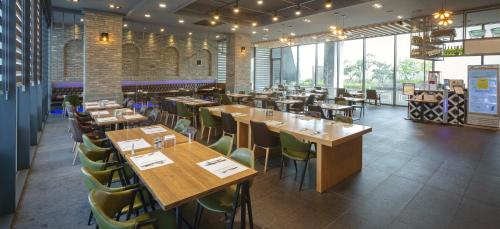 un restaurante con mesas de madera y sillas verdes en Grand City Hotel Changwon, en Changwon