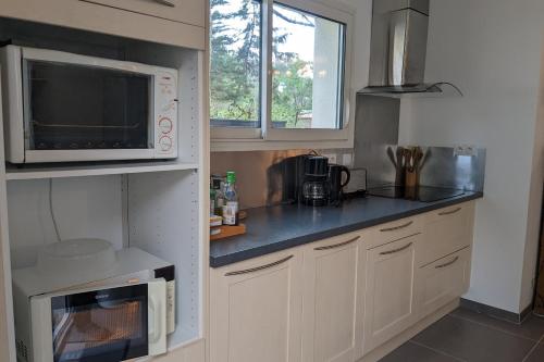 una pequeña cocina con armarios blancos y microondas en Nice 90m near the surf beach of Bud, en Longeville-sur-Mer