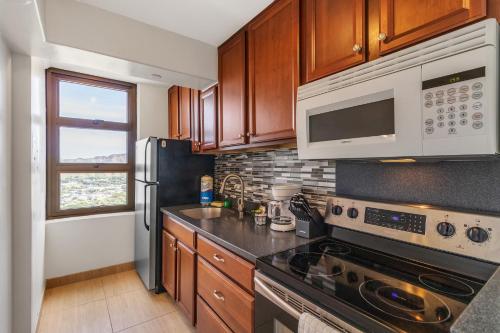 a kitchen with a stove and a microwave at 37th Floor Condo with Sweeping Ocean Views & Free parking! condo in Honolulu