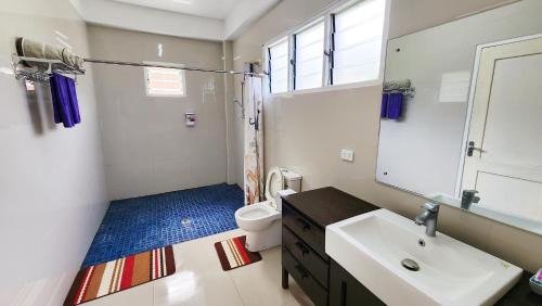 een badkamer met een wastafel, een toilet en een spiegel bij Pacific Paradise Villa in Sigatoka