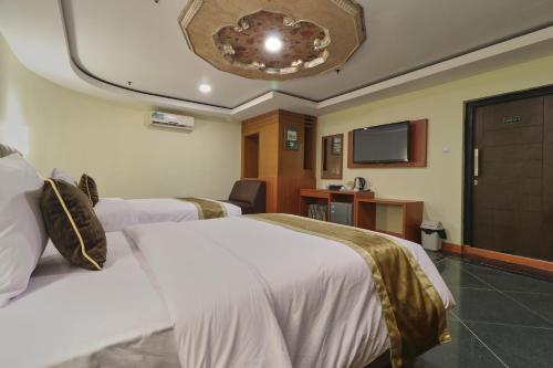 a hotel room with two beds and a flat screen tv at Coins Hotel Jakarta in Jakarta