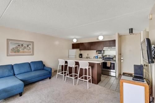 uma sala de estar com um sofá azul e uma cozinha em Waikiki Banyan 28th Floor Ocean View Condo - Free parking & WiFi home em Honolulu