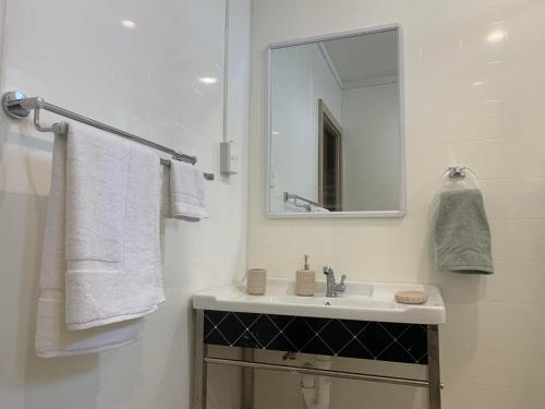 a white bathroom with a sink and a mirror at Samoa Business Apartments 2 in Apia