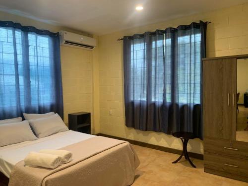 a bedroom with a large bed with blue curtains at Samoa Business Apartments 2 in Apia