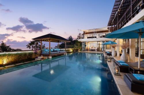 a large swimming pool with blue water in front of a building at Villa Jamalu by Nakula in Jimbaran