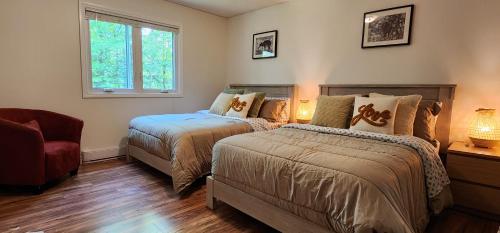 a bedroom with two beds and a chair and a window at Private 5 BR Muskoka Cottage Firepit+BBQ+Wi-Fi in Bracebridge