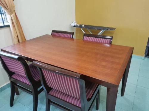 a wooden table with four chairs around it at Teratak Tuan Muda Homestay in Melaka