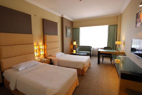 a hotel room with two beds and a television at Dynasty Hotel Miri in Miri
